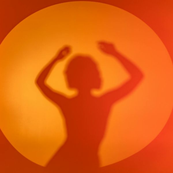 Woman performing a light, graceful movement in a bright room.